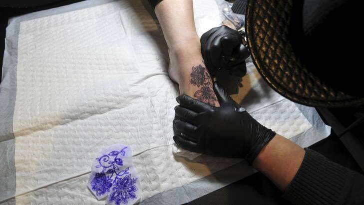A customer receives a tattoo at the Tatts on Tatts off tattoo parlour in Gungahlin, which has re-opened for business. Photo: Melissa Adams