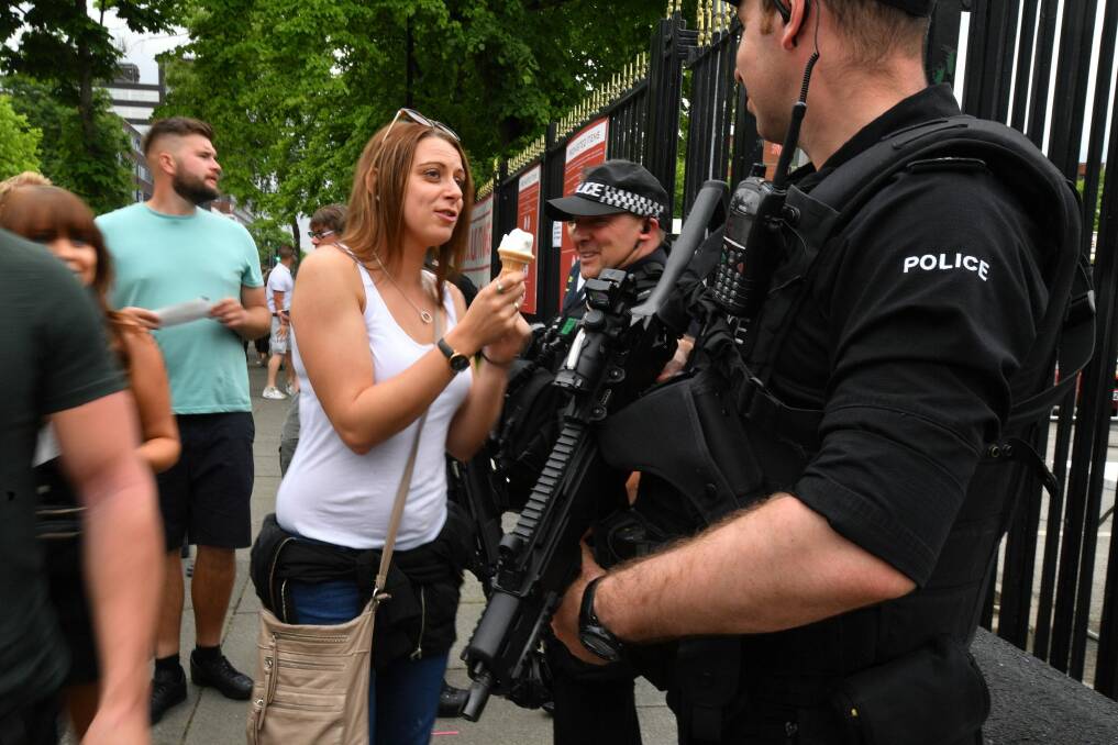 A woman offers her ice cream to a police officer as armed police patrol around Old Trafford Cricket Ground ahead of a Courteeners concert ahead of the One Love benefit set to take place on Sunday night. Photo: Anthony Devlin