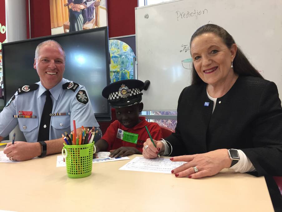 Acting Superintendent Jason Kennedy, North Ainslie Primary School student Chan Arak, 7, and Crime Stoppers ACT region chair Diana Forrester work on the 2018 Crime Stoppers Week colouring in competition. Photo: Blake Foden