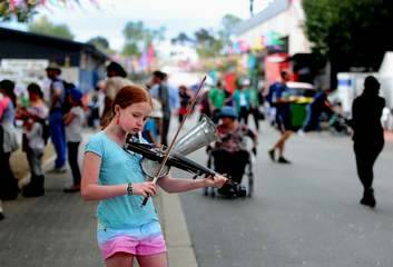 Claire Doherty, 11, busks at the National Folk Festival, Canberra with her Stroh Violin. Photo: Melissa Adams