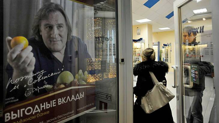 People pass by an advertisement poster of a small Russian bank showing Gerard Depardieu. Russians reacted with amusement, disbelief and a heavy dose of irony to the news that the Kremlin has granted citizenship to French actor Gerard Depardieu to solve his tax woes. Photo: Olga Maltseva