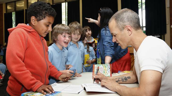 Ainslie School year 3 students Omar Algothmi, Benjamin Coram and Issac Jario get their books autographed by author Andy Griffiths following his visit to the school. Photo: Jeffrey Chan