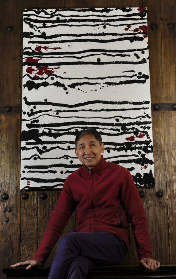 Hou Leong with his work <i>24 Black Horizontal Lines on White</i> at The Silk Road Gallery. Photo: Graham Tidy