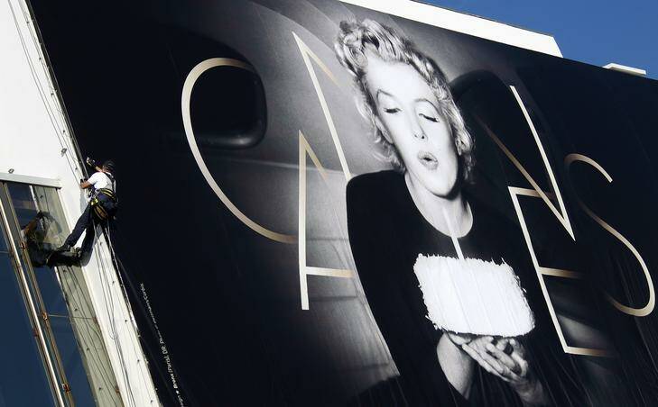 A worker sets up a giant canvas of the official poster of the 65th Cannes Film Festival featuring  U.S. actress Marilyn Monroe on the facade of the Festival Palace in Cannes May 14, 2012. Photo: Reuters