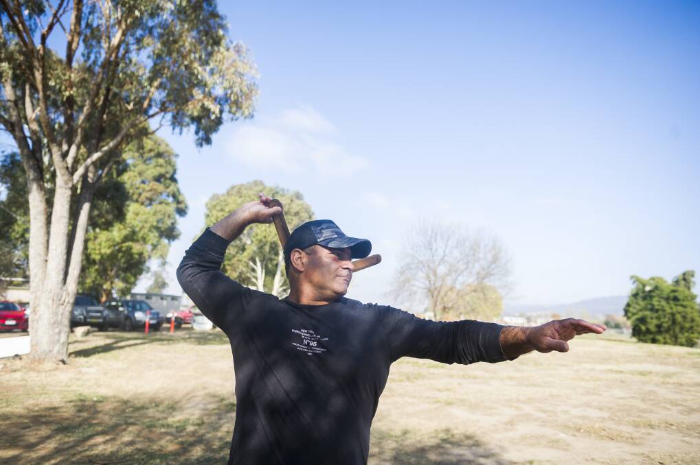 Ngunnawal man Richie Allen teaching the families how to throw a boomerang.  Photo: Dion Georgopoulos