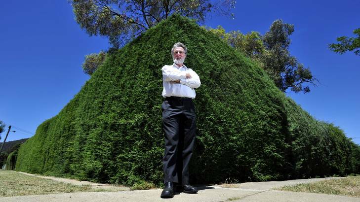 Leon Arundell of the North Canberra Community Council is forced to walk on the grass due to the over grown hedge that covers the footpath on Chapman Street in Braddon. Photo: Jay Cronan