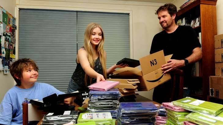 Daniel Billing of Downer and his kids Luka,10 and Hannah,16 packing kindles to send to indigenous children all over the country. Photo: Melissa Adams