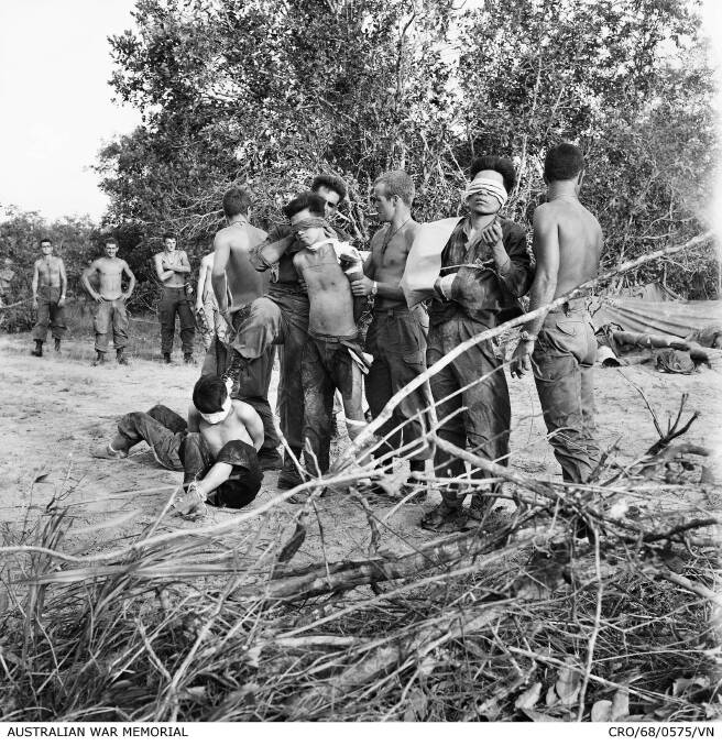 Bien Hoa Province, South Vietnam: Blindfolded North Vietnamese soldiers captured on May 28, 1968, await helicopters to take them from the battle area. Photo: AWM