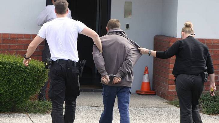 Detectives escort a 28-year-old man arrested over a Wynnum West home invasion into Cleveland Police Station on Wednesday afternoon. Photo by Stephen Jeffery Photo: Stephen Jeffery