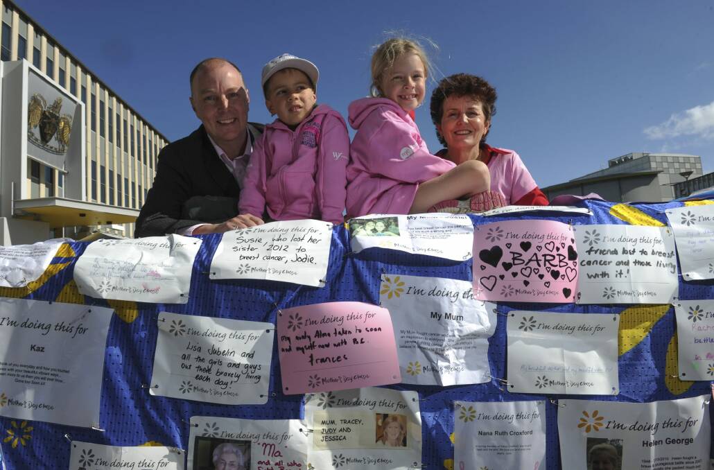 Trevor Hickman, of Curtin, with his children, Elijah, 6, and Audrey, 7, at the tribute wall for the Mother's Day Classic. Mr Hickman lost his wife, Amy, to breast cancer. Ms Hickman's friend, Barb Miels-Barrett (right), of Kambah, will take part in the charity event this year. Photo: Graham Tidy