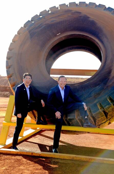 Tony Abbott and Japanese Prime Minister Shinzo Abe pose for a photograph next to a haulage truck tyre during a tour of an iron ore mine in the Pilbara in July last year. Two months earlier Mr Abbott paid nearly $2500 to keep a set of bicycle wheels gifted by Mr Abe.  Photo: Getty Images