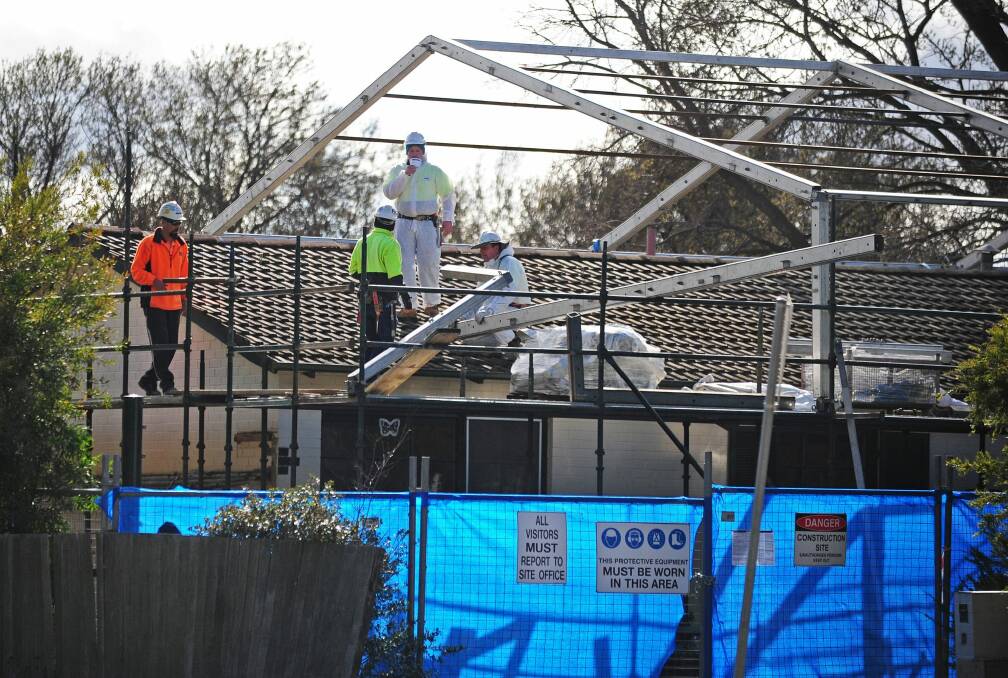 Asbestos removal from a house in Downer in 2013. Workers construct a steel frame where a plastic shield will be stretched over the house for the removal of asbestos.  Photo: Katherine Griffiths