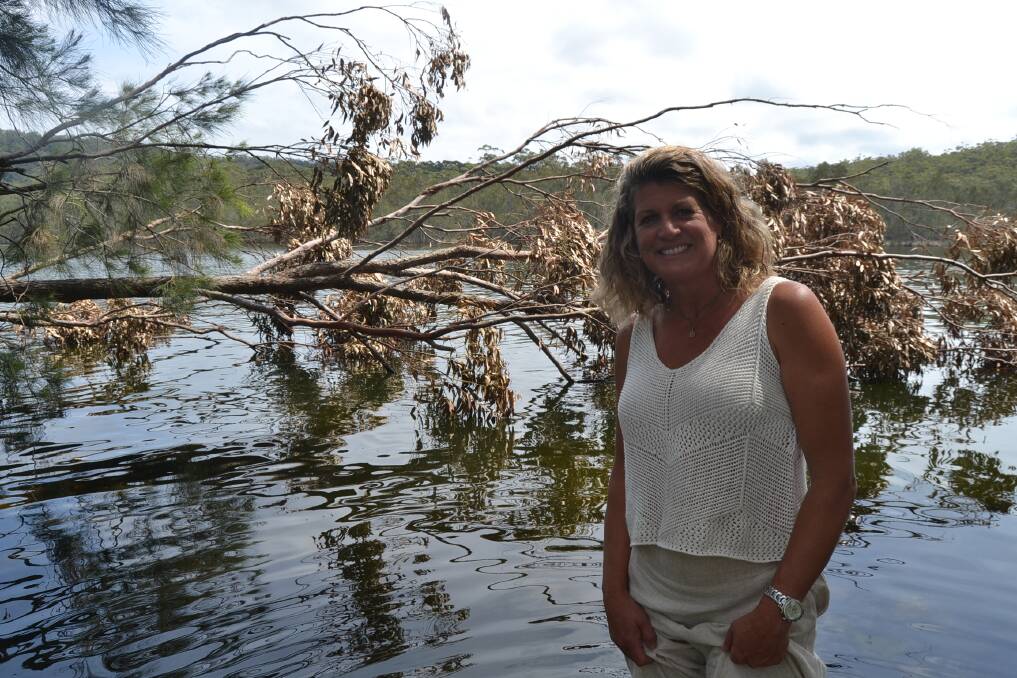 Lake Conjola resident Kristen Bird by a fallen tree which she said collapsed into the water from flooding. Photo: Sam Strong