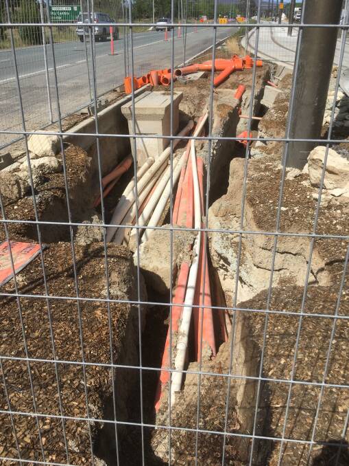 A pit near the intersection of the Federal Highway and Flemington Road, where electrical cables appear to be installed just a few millimetres below ground level.