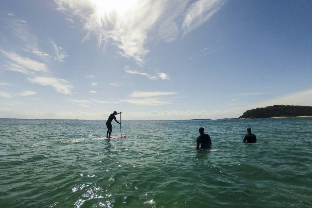 Stand up paddle boarders and surfers at Lake Tabourie on the South Coast of NSW. Photo: Jay Cronan