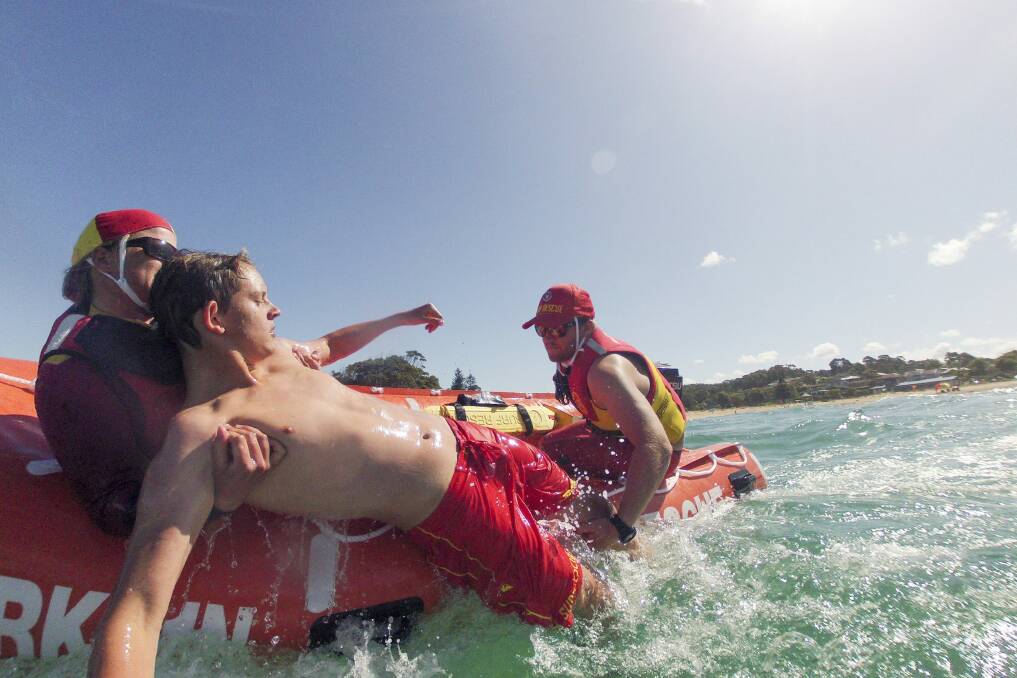 Sam Sharkey of Malua Bay plays the role of troubled swimmer for surf lifesavers Kirsty Moore (front of the boat), and Josh Crouch (driving the boat) to practise their IRB rescues. Photo: Jay Cronan