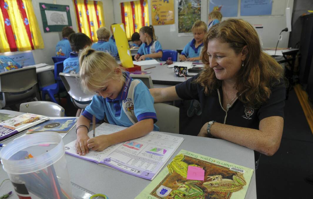 Seven-year-old Mia Chambers of Brisbane, gets on with her work under the watchful eye of teacher, Lisa Calkins, in the mobile classroom. Photo: Graham Tidy
