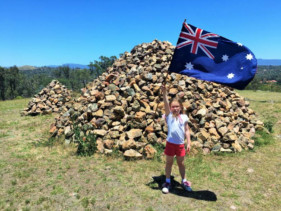 Emily flies the Australia flag at the mystery rock cairns atop Gossan Hill. Photo: Tim the Yowie Man