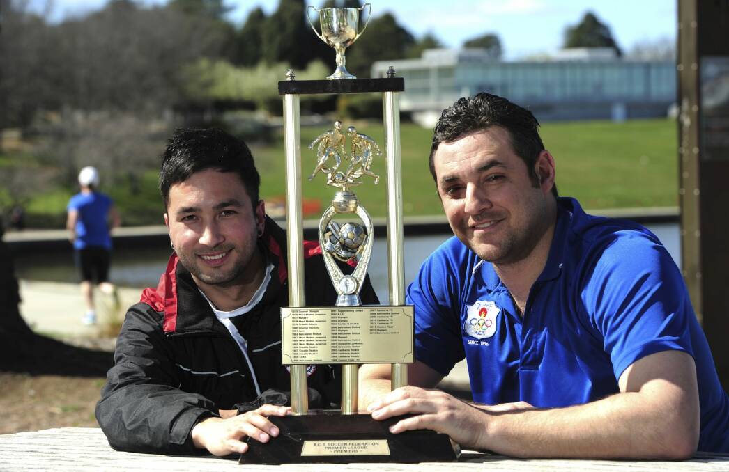 Canberra FC captain Aidan Brunskill and Canberra Olympic skipper Angelo Konstantinou with the trophy they will be playing for in Sunday's ACT NPL grand final. Photo: Graham Tidy
