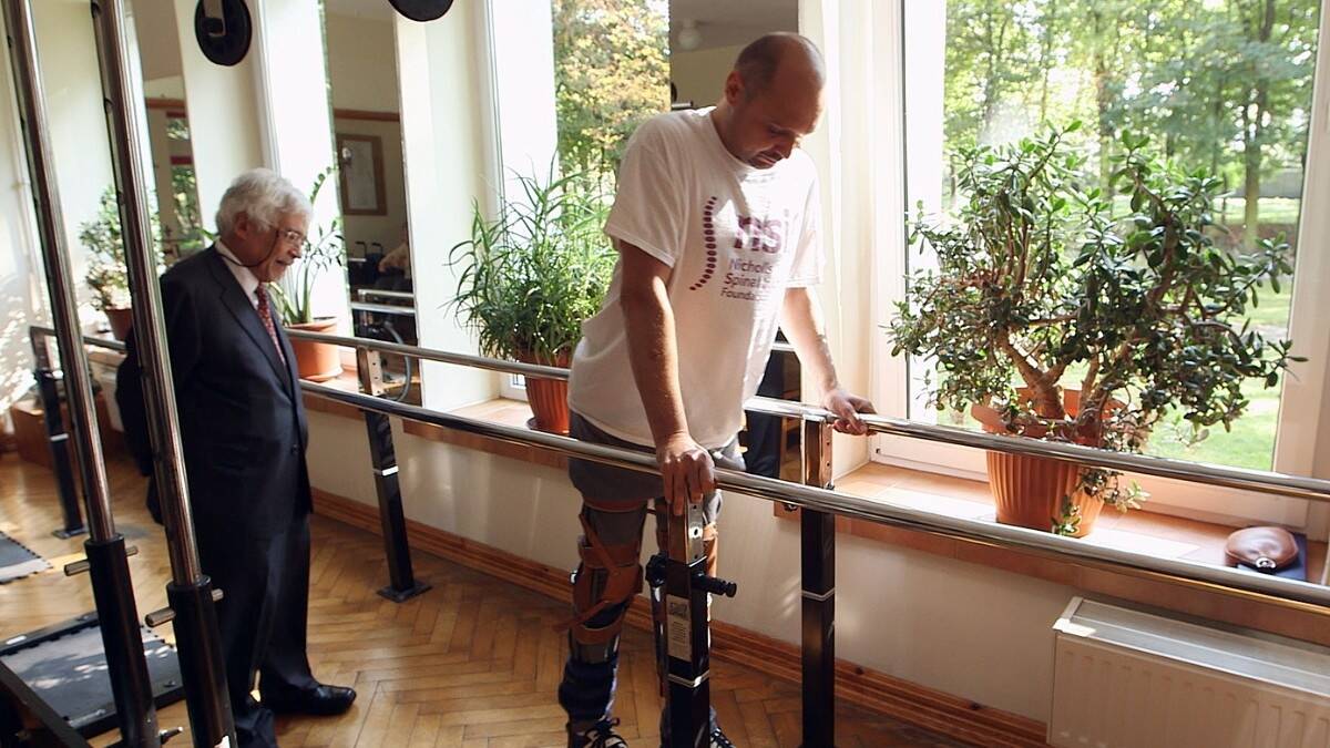 Darek Fidyka walks with the assistance of parallel bars and leg braces. Photo: BBC