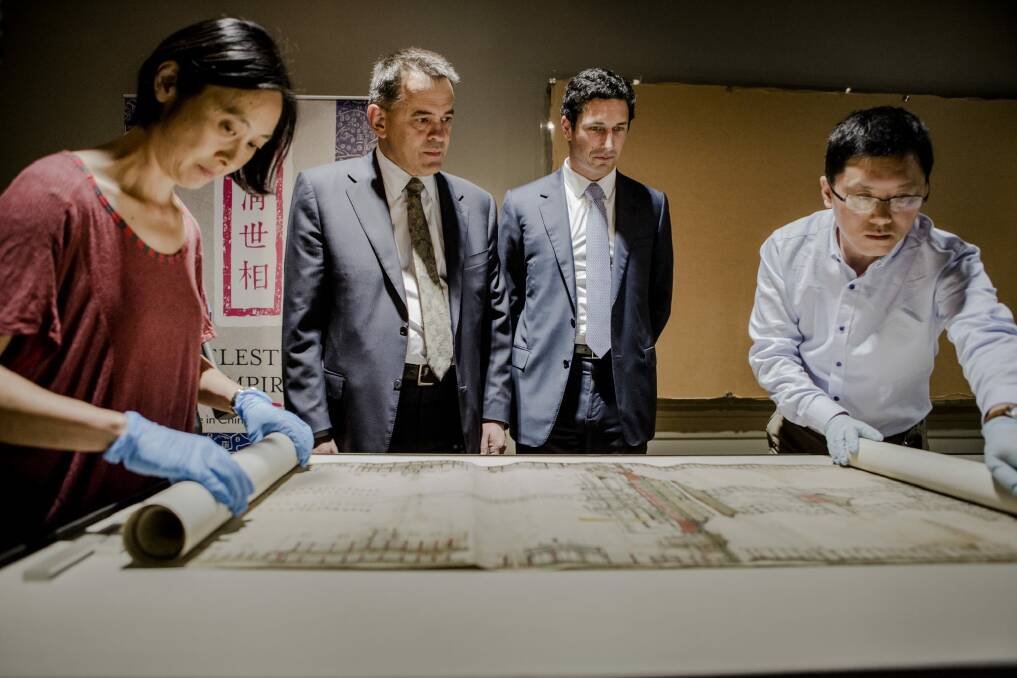 The National Library of Australia's preservation manager Lisa Jeong-Reuss and National Library of China Conservator Zhu Zhenbin
unfurl the plan of the Forbidden City Palace at the launch of "Celestial Empire: Life in China 1644-191", while MLA Chris Bourke and NLA council chairman Ryan Stokes look on. Photo: Jamila Toderas