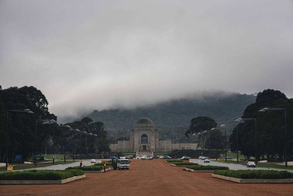 Fog rolls in on Anzac Parade as workers tidy the gardens ahead of Anzac Day. Photo: Rohan Thomson