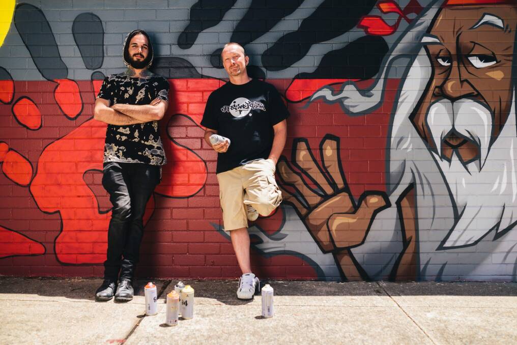 Brett David Carpenter, left and  Matthew Peet   at the Kippax shops toilet block they have helped paint with involvement from young Indigenous Canberrans. Photo: Rohan Thomson