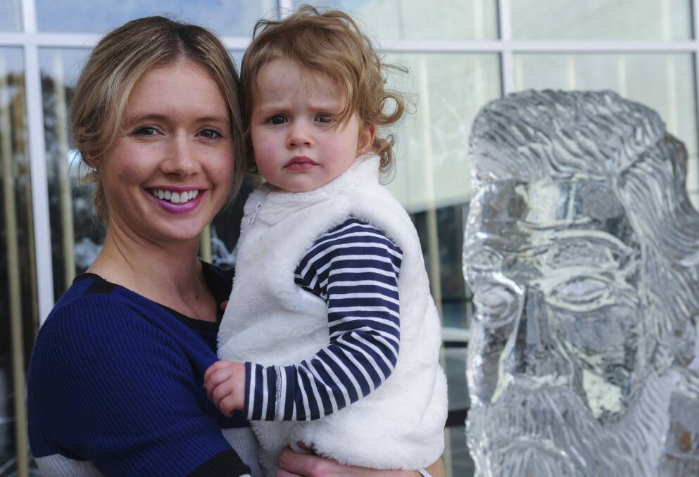Michelle Cooper, of Weston Creek, with her daughter Jade, 18 months, rugged up beside a fleeting ice sculpture of Sir Henry Parkes, who was born 200 years ago. Photo: Graham Tidy