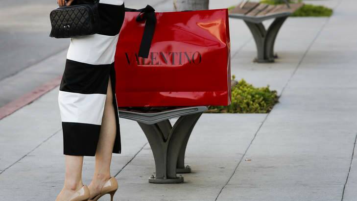 A woman holds a purse while standing next to Valentino Fashion Group SpA shopping bag. Photo: Patrick Fallon