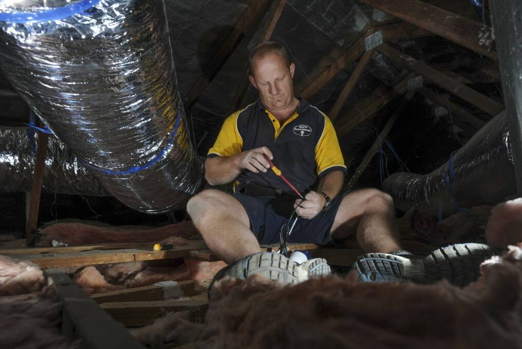 Electrician Paul Callaway in the roof space of a home in Weston. He says he has no doubt been in Mr Fluffy homes during his 20-year career. Photo: Graham Tidy