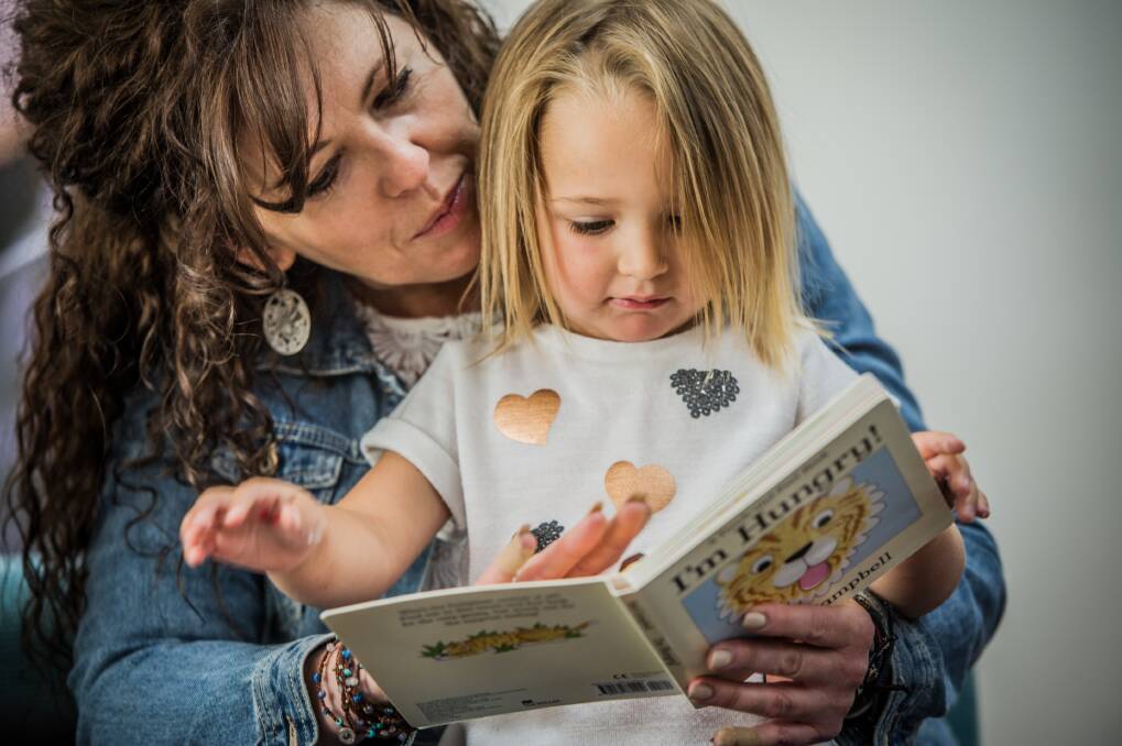 Jodie Perry reads to three-year-old Grace Ryan, of Banks. Children from the preschool at the Canberra College attended The Smith Family Christmas Appeal launch.
 Photo: Karleen Minney