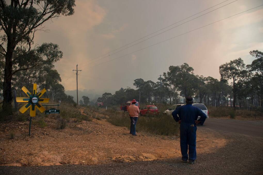 Vanessa and Kevin Lesley watch on as the fire burns in the distance, shortly before their own property was destroyed. Photo: Jay Cronan