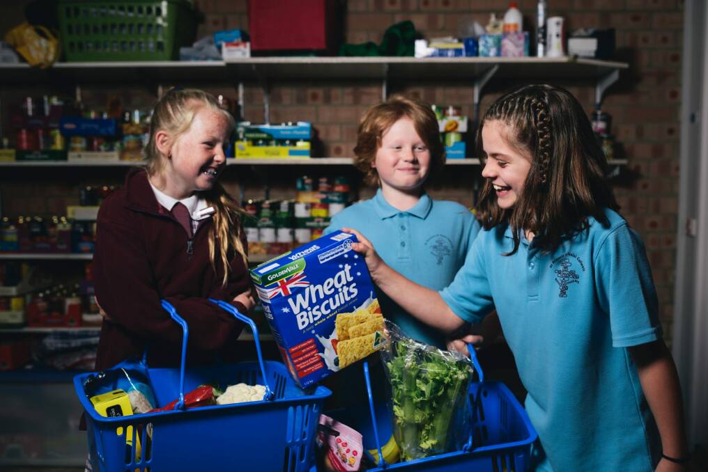 St Francis year 5 students Tiana Boots, Dean Lawrence, and Sarah Matthews organise groceries for St Vinnies as part of the Vinnies Christmas Appeal. Photo: Rohan Thomson
