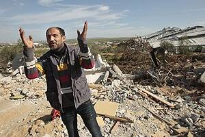 Raed al-Athamna stands by the ruins of his destroyed house in Gaza.