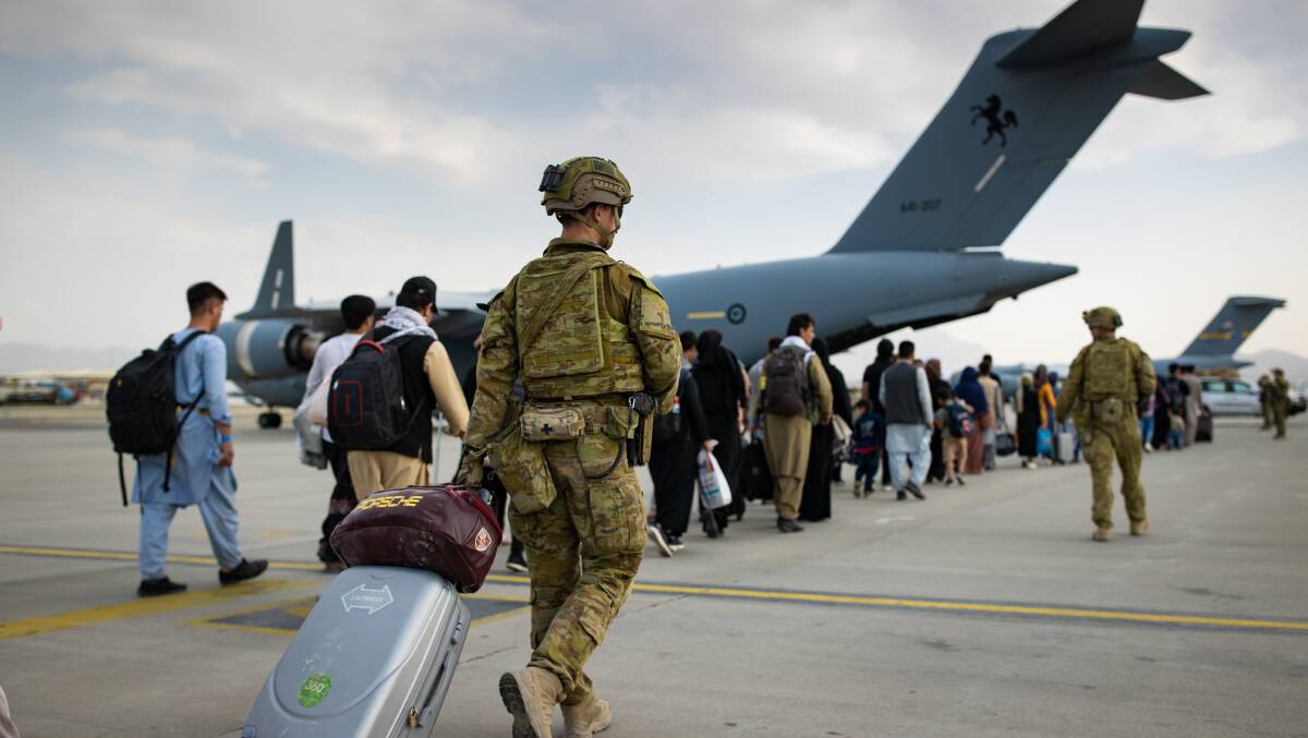 Australian citizens and visa holders prepare to board the Royal Australian Air Force C-17A Globemaster III aircraft, as Australian Army infantry personnel provide security and assist with cargo at Hamid Karzai International Airport, Kabul. Picture: Department of Defence