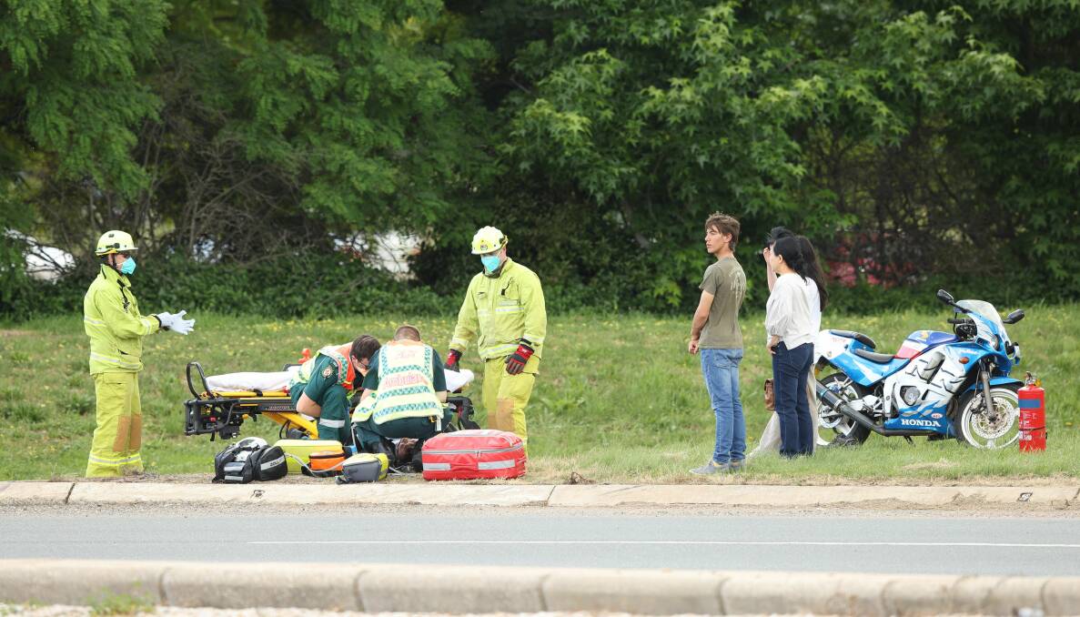 Paramedics at the scene of a motorbike crash at the roundabout at the intersection of Parkes Way and Coranderrk Street. Picture: Sitthixay Ditthavong.