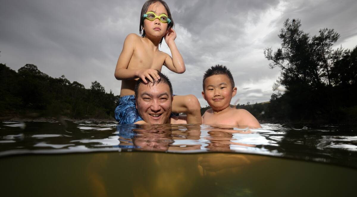 Charles Liang from Denman Prospect takes a dip at Uriarra with nephew Ethan Nuk, 8, and son Lucas, 7 (right). Picture by Sitthixay Ditthavong
