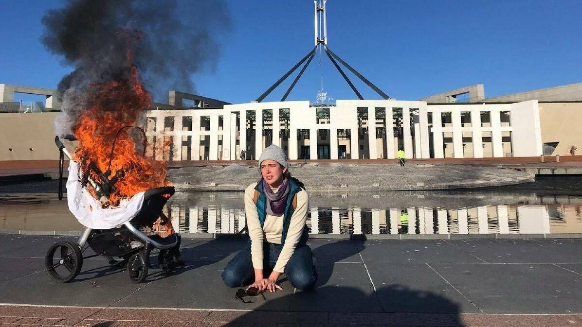 Extinction Rebelion member Violet Coco beside a burning pram outside Parliament House. Picture: Supplied