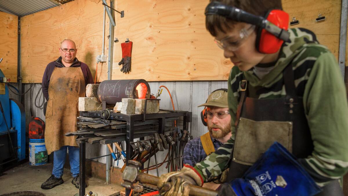 Tharwa Valley Forge owner Karim Haddad (left) watches as Geordie Price (right) participates in a Defence family blacksmithing course under the instruction of Charlie Walker (centre). Picture by Sitthixay Ditthavong