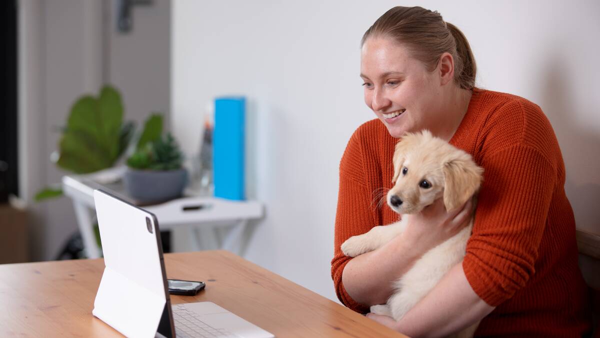 Laura Wilson with her puppy Sadie connects with a friend via videocall. Picture: Sitthixay Ditthavong