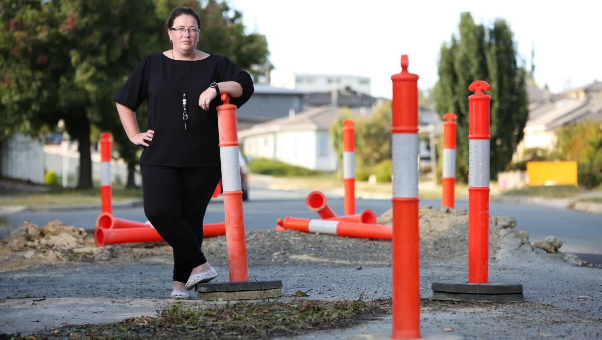Kellie Baker standing beside a huge pothole in Tarra Place, Ngunnawal. Picture: James Croucher