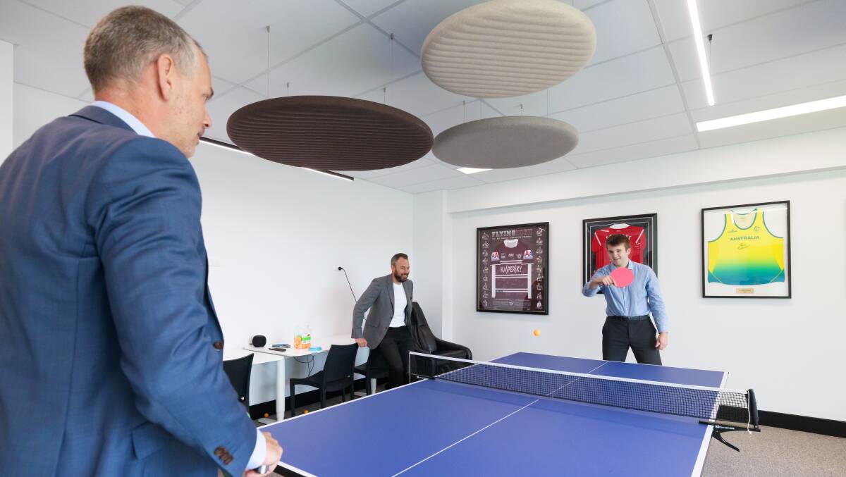 Ray White Canberra's Alec Brown, centre, watches colleagues Troy Reddick and Archie Cheeseman battle it out on the ping pong table at their Tuggeranong office. Picture by Sitthixay Ditthavong
