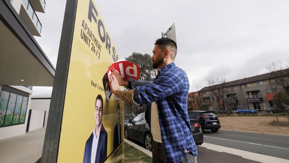 Canberra buyer Michael Vella puts the sold sticker on his new property purchase. Picture by Keegan Carroll