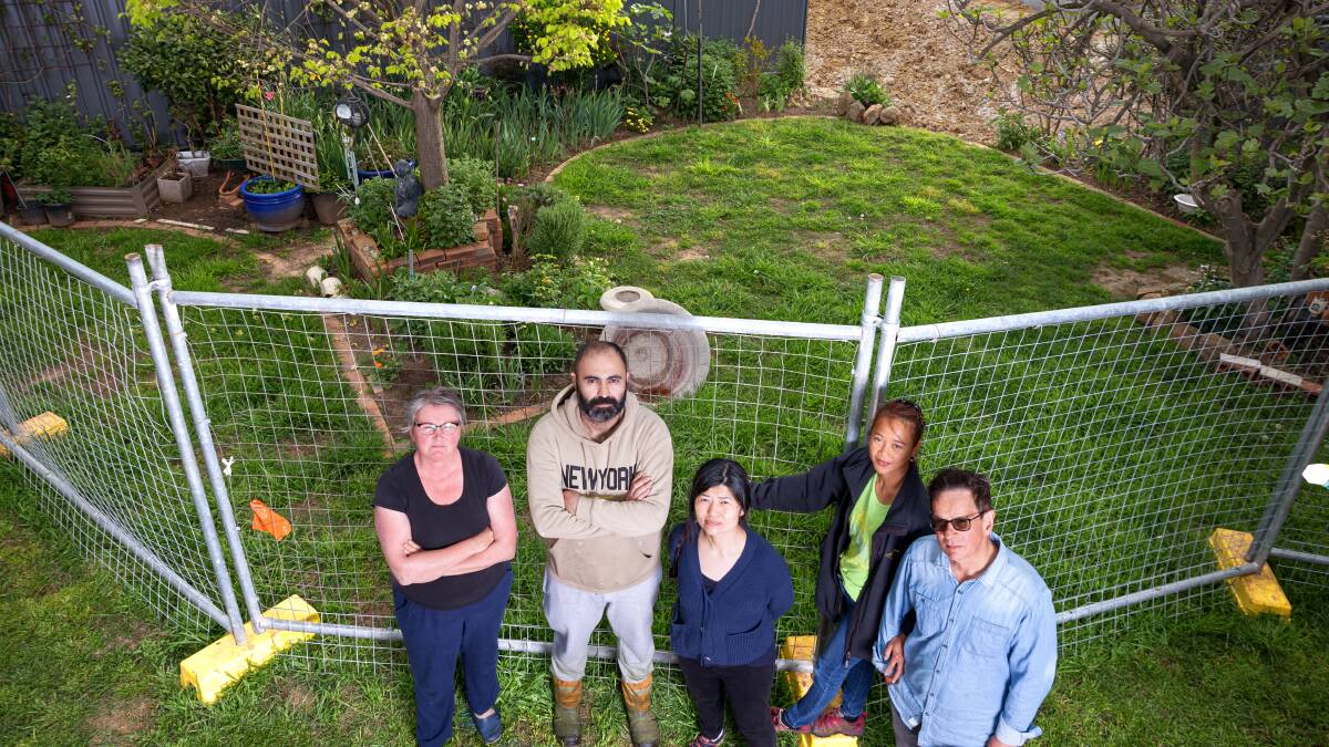 Dickson home owners Carleen Jones, Jack Kourie, Yvon Li, Irene Barber and Alan Barber standing in front of a backyard that fell into an excavation pit. Picture by Sitthixay Ditthavong