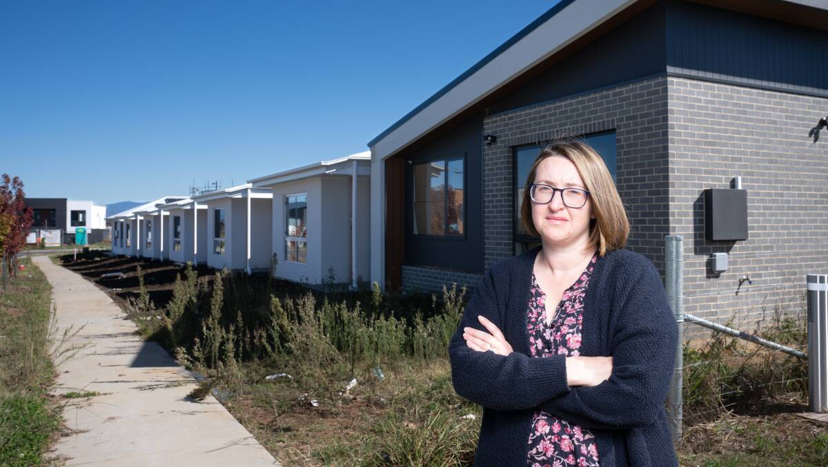 Rebecca Lewis in front of a row of affordable houses in Whitlam, where she expected to live. Picture by Sitthixay Ditthavong