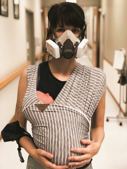 Professor Gemma Carey holding her newborn while wearing a respirator mask to protect herself from COVID. Picture supplied. 