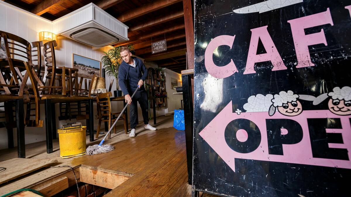 Merino Cafe's Corey Plumb cleans up in the aftermath of Monday night's deluge which flooded the cellar. Picture by Sitthixay Ditthavong