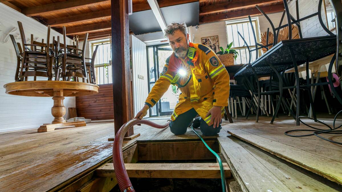 A NSW Rural Fire Service Officer pumps out water from the cellar of Merino Cafe. Picture by Sitthixay Ditthavong