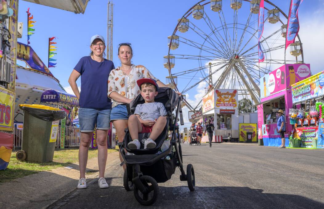Laura, Grace and Oliver Wilson-Dennis, 3, check out sideshow alley. Picture by Keegan Carroll