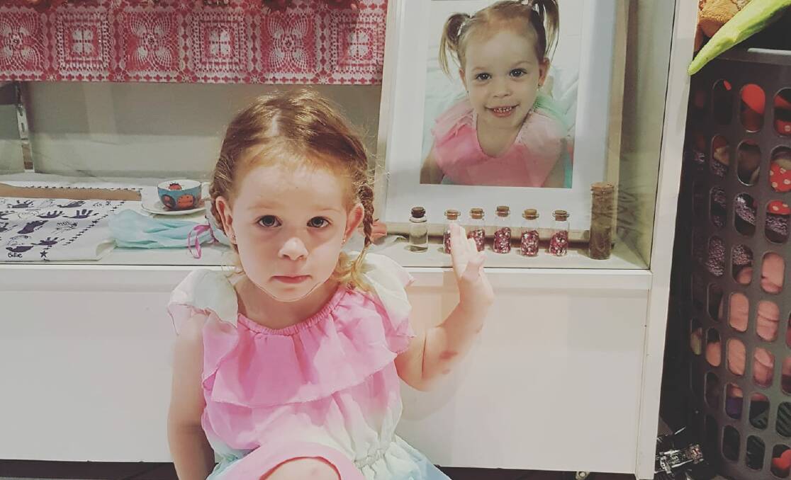 Rhainer Lawrence with a photo of her late twin sister Skylar who died of meningococcal disease aged 33 months. 